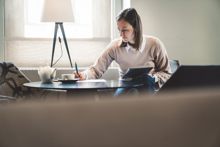 A female aspiring private investigator taking some by pen and holding a tablet