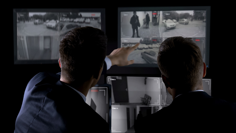 private investigator viewing surveillance monitors