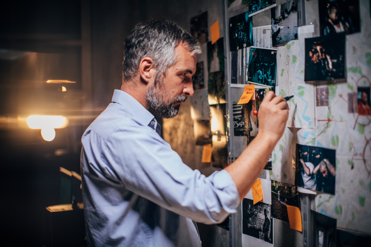 Private detective looking at map on a pegboard