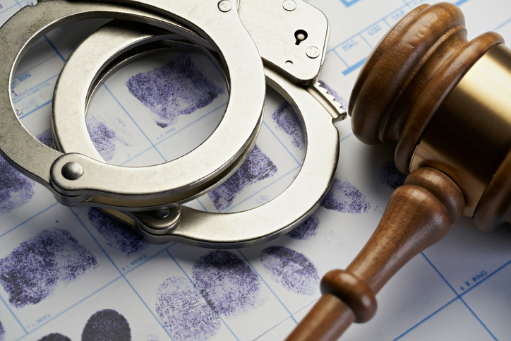 Handcuffs and gavel on fingerprint sheet