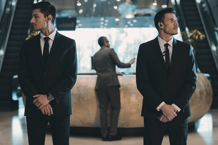 Two private security men standing in suites in the lobby of a hotel